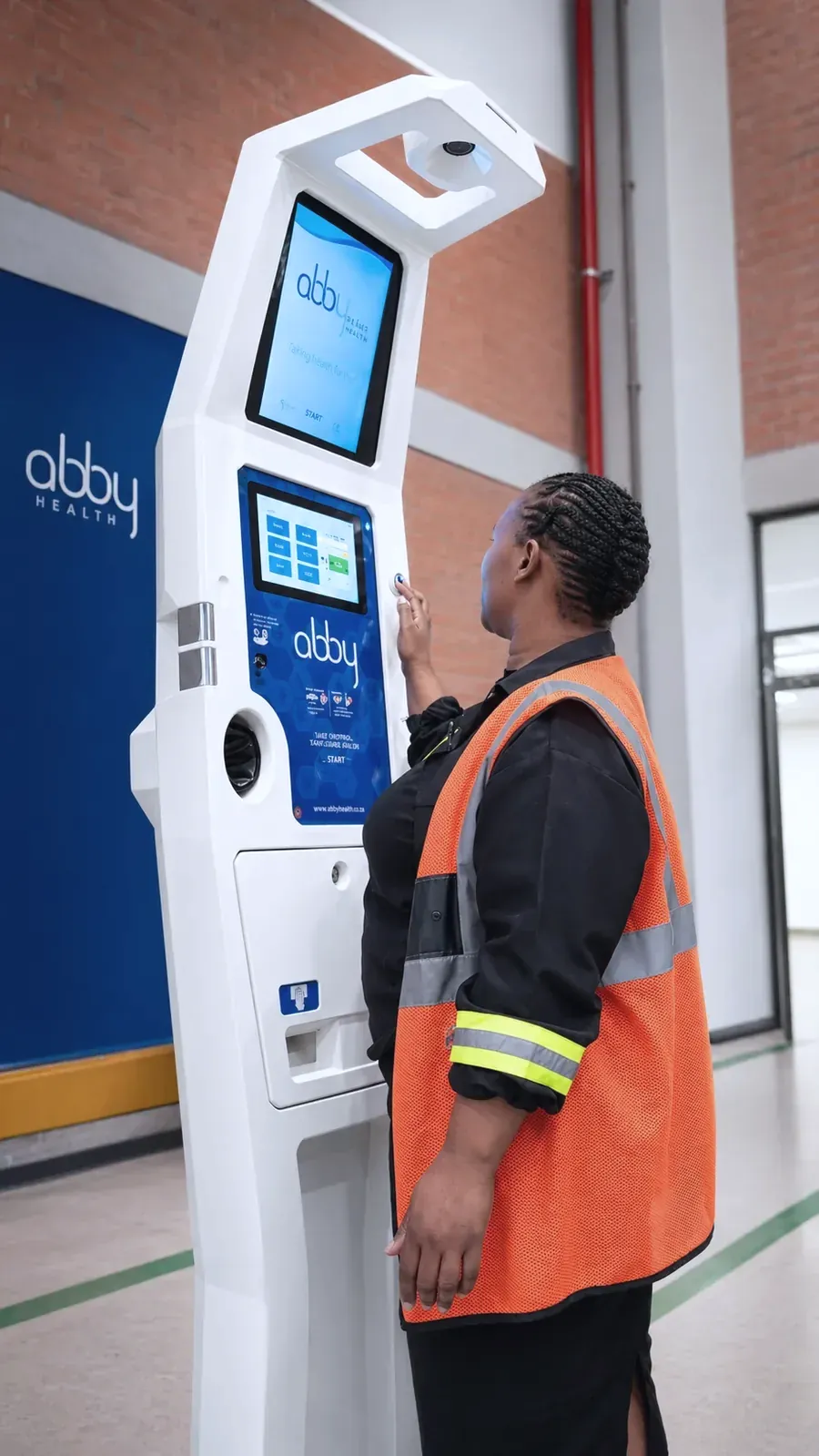 A worker in hi vis using an Abby Health Station